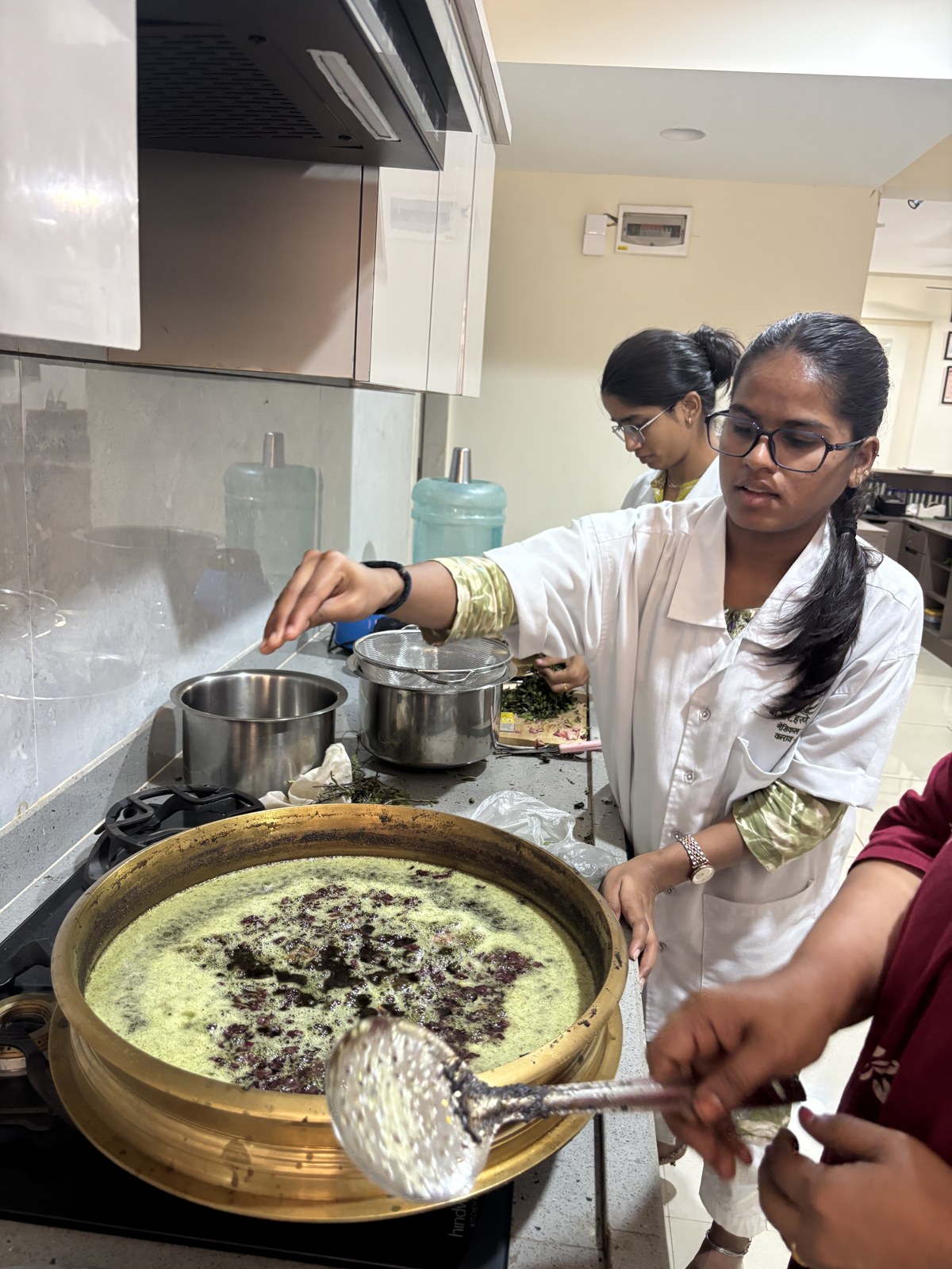 Clinic team stirring a herbal preparation in the Ashtaang preparation area